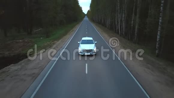 在夏季森林中的乡村道路上驾驶白色高级轿车视频的预览图