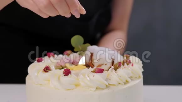 糖果师用磨碎的杏仁和椰子洒在蛋糕上一只手的特写和倒屑视频的预览图