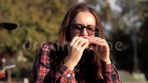 年轻女孩坐在公园里聊天吃土豆和酱汁和三明治去吃饭度假视频的预览图