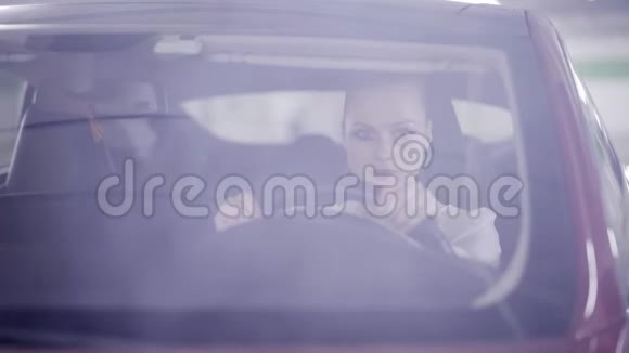 坐在红色轿车里坐在方向盘后面微笑的马尾女孩视频的预览图