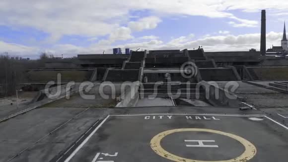 早春在灰色的大型建筑群附近的直升机停机坪和两部楼梯与蓝色多云的天空对峙视频的预览图