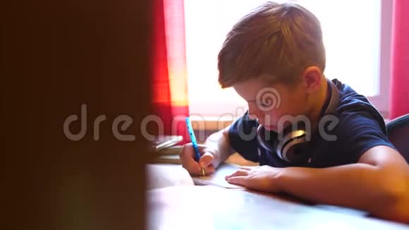 男孩坐在学校的桌子上做这份工作学校教育太阳透过玻璃的光线视频的预览图