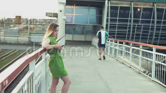 城市里的年轻女孩带着智能手机读信息看过去的人日落视频的预览图