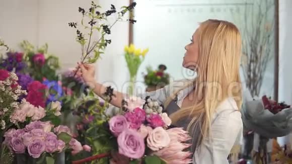 专业的金发女性花艺师在花店布置漂亮的婚礼花束手工制作和花艺视频的预览图