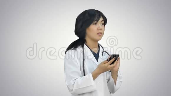 在白色背景下使用智能手机的亚洲女医生视频的预览图