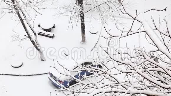 在一个有雪覆盖的树木的冬季公园里雪下的汽车和木制桌子视频的预览图