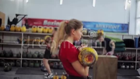 年轻女子运动员用水壶铃进行长周期推在健身房做健身运动的女孩视频的预览图