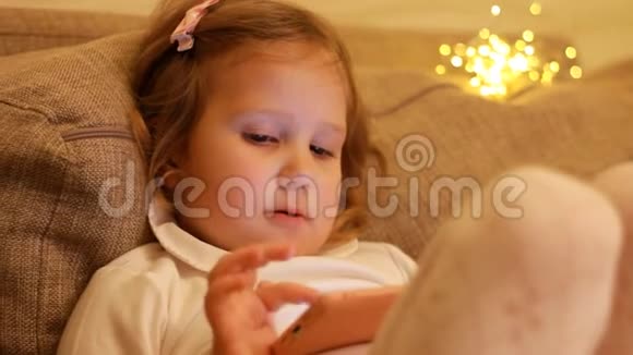 小女孩玩智能手机宝贝在手机上看视频的背景灯boke视频的预览图