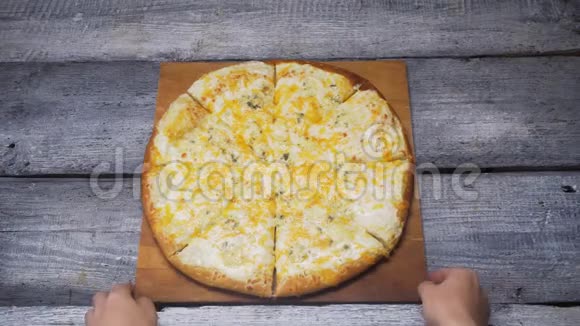 热的四个奶酪美味的披萨躺在托盘上的木材灰色板背景框架把手举起来视频的预览图