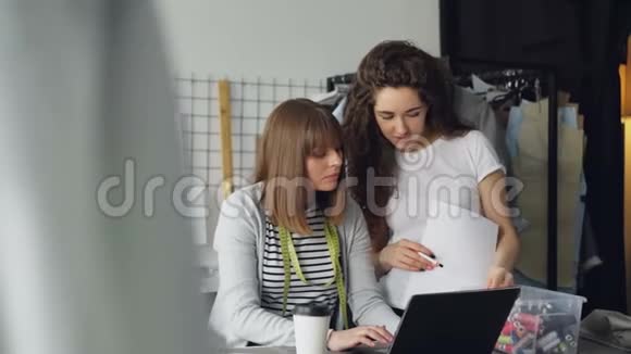 两位迷人的女裁缝正在看手提电脑并在屏幕上选择缝纫线创造新环境视频的预览图
