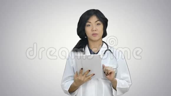 女医生拿着数码平板电脑在白色背景下看相机视频的预览图
