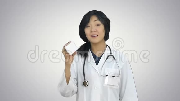 女医生举着一盒药片微笑着把它呈现在白色的背景上视频的预览图