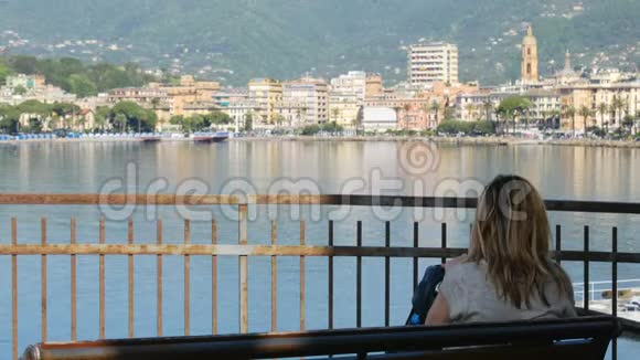 女子坐凳城市海湾天际线后景意大利里维埃拉视频的预览图