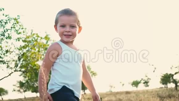 一个活泼开朗的孩子在自然背景上的肖像小男孩微笑着看着相机快乐的童年视频的预览图