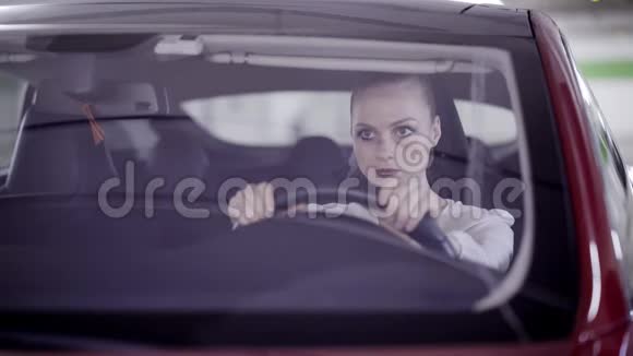 梳着马尾辫的年轻女性坐在红色的车里摇着头在方向盘后面视频的预览图