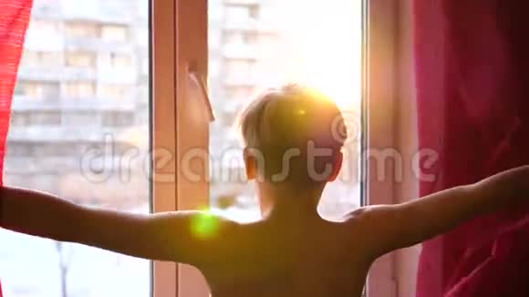 那家伙一大早就来到窗户前拉开窗帘太阳光线穿过玻璃视频的预览图