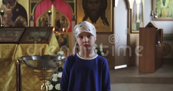 一个穿着围巾和蓝色裙子的悲伤小女孩正在教堂里祈祷视频的预览图
