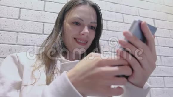 微笑的女人正在手机上输入一条信息坐在咖啡馆里等人视频的预览图