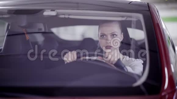 梳着马尾辫的年轻女性坐在红色的车上笑在方向盘后面视频的预览图