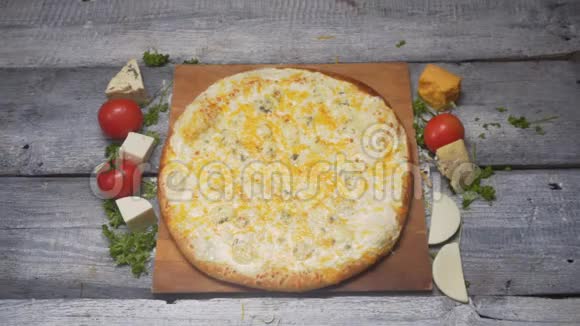 在木切割板上贴上美味的新鲜意大利四奶酪比萨饼在一个木切割板上贴上西红柿和奶酪视频的预览图