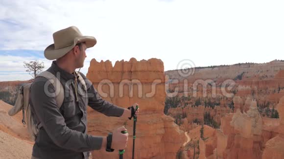 一个穿着牛仔帽的徒步旅行者在峡谷的风景中寻找视频的预览图
