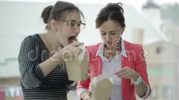 办公室午休两个商务女性正在吃中国面条站在窗口交流视频的预览图