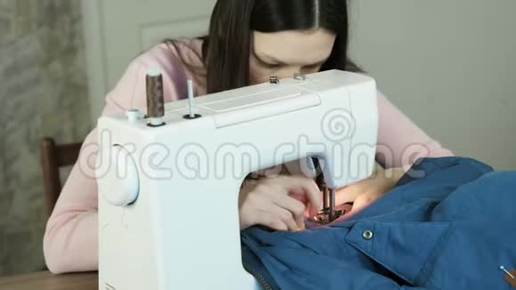 年轻女子在白色缝纫马什尼上缝制蓝色夹克看看她的作品视频的预览图