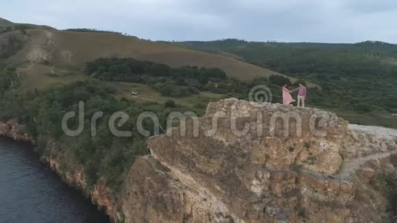 一对相爱的情侣站在悬崖上享受大自然视频的预览图