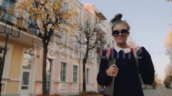 漂亮的时髦少女走在老城街上微笑着手拿手提电脑的红包女学生视频的预览图