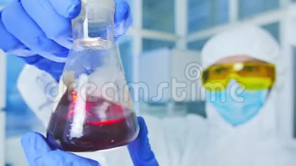 化学实验室实验室烧瓶中分析液体的研究员视频的预览图