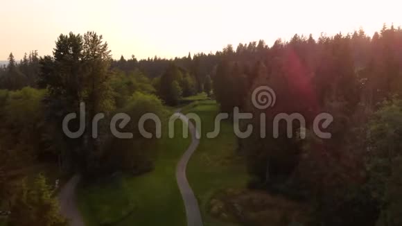 一个高尔夫球场的航拍镜头坐落在一片常绿森林里高尔夫球手在球道和果岭上打球视频的预览图