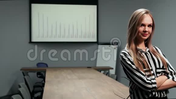 一位身穿办公室服装的金发商务女性站在办公室的一张大桌子上的画像和上面的图表视频的预览图