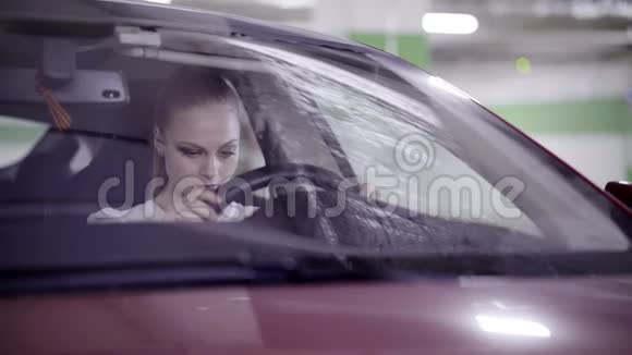穿着白色衬衫的漂亮女人坐在红色的车里手里拿着方向盘视频的预览图
