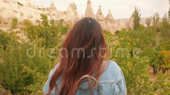 在土耳其卡帕多西亚年轻的混合种族旅游女孩用手机拍摄美丽的山岩照片4K慢动作视频的预览图