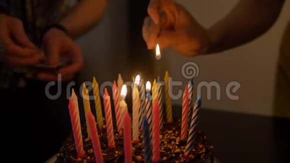 男女在美味的生日蛋糕上点蜡烛准备参加聚会视频的预览图