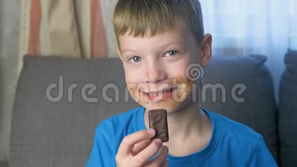 格里米快乐的少年正坐在沙发上吃巧克力糖不健康饮食观念视频的预览图