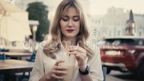 在巴黎年轻的白人金发女人卷发红唇戴着智能手表通过视频的预览图