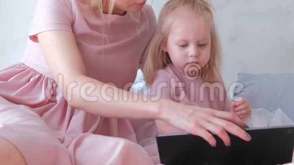小可爱的金发女孩和她妈妈一起在平板电脑上选择一个应用程序视频的预览图