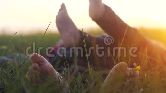 快乐家庭孩子的概念赤脚的孩子们躺在草地上在公园的草坪上休息玩耍视频的预览图