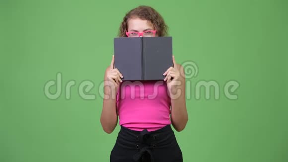 年轻害羞的书呆子一头卷发躲在书后面视频的预览图
