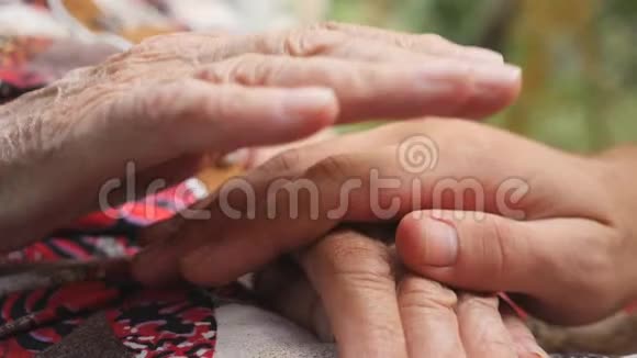 年轻的男性和皱纹的手安慰和抚摸对方户外孙子和奶奶花时间视频的预览图