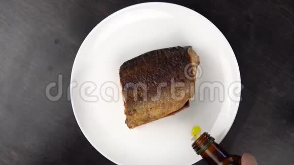 白色盘子上的一片炸红鱼在黑桌上旋转视频的预览图