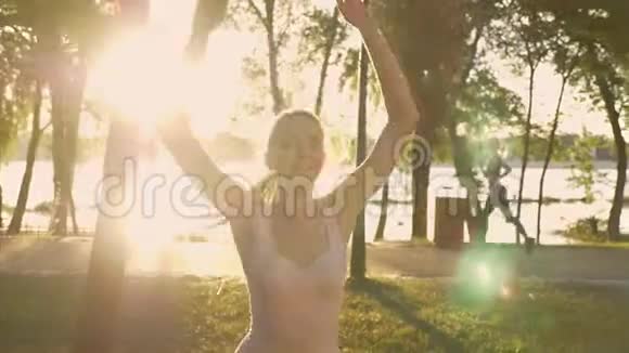 年轻女子在公园做明星运动健身模特跳跃其他女子背部跑步镜头耀斑美丽的景色视频的预览图