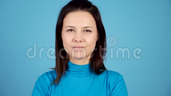 慢动作的女人在蓝色背景下对着镜头微笑视频的预览图