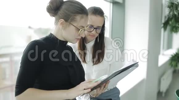 两位女商人研究了办公室窗口的市场趋势视频的预览图