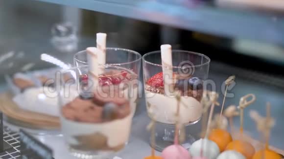 一位女士正在餐厅的厨房里从糖果棒里端着一杯带有新鲜浆果的甜点视频的预览图