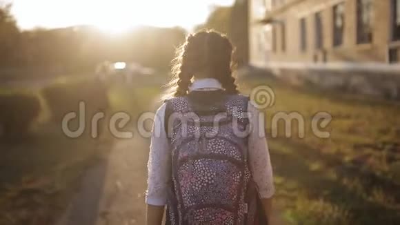 女朋友带着背包的女学生在夕阳下从学校回家从背面看到视频的预览图