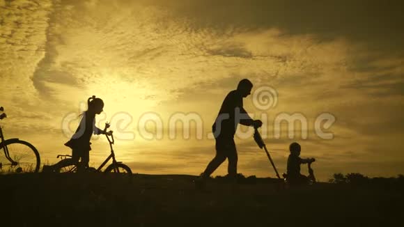 比基尼家庭剪影父母带着两个孩子骑自行车在日落友好家庭观念视频的预览图