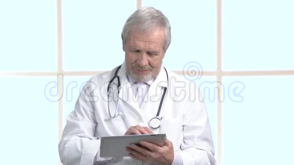 年纪较大的医生在做电脑平板电脑视频的预览图