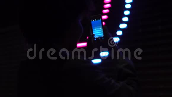 在智能手机夜间照明假日等节目上拍摄女孩影片的剪影视频的预览图